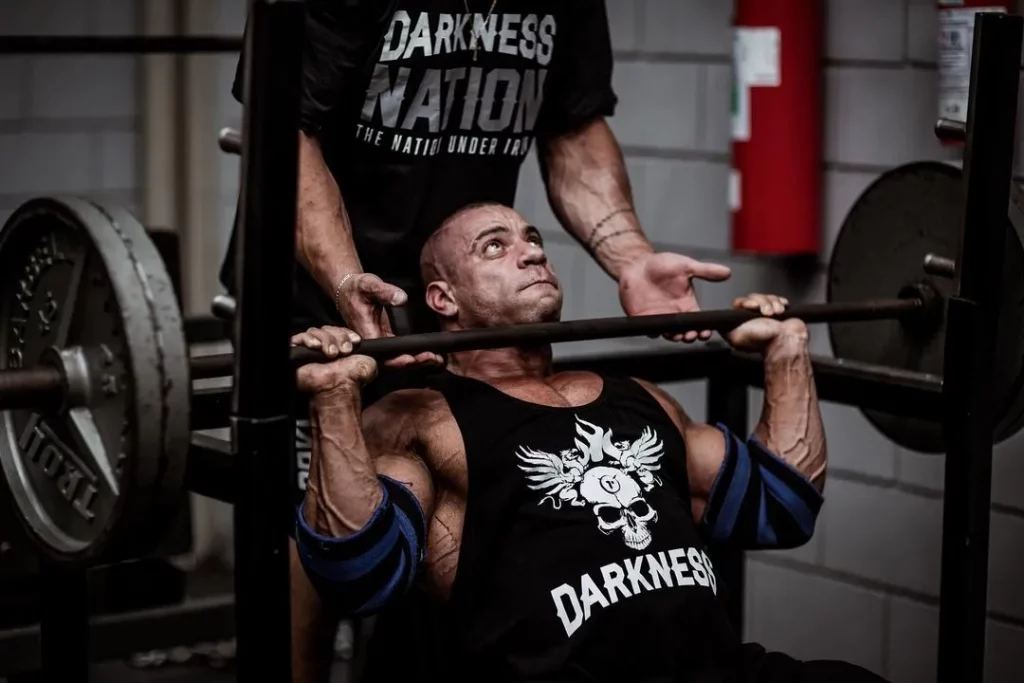 atleta bodybuilder fazendo treino de peito com uma barra